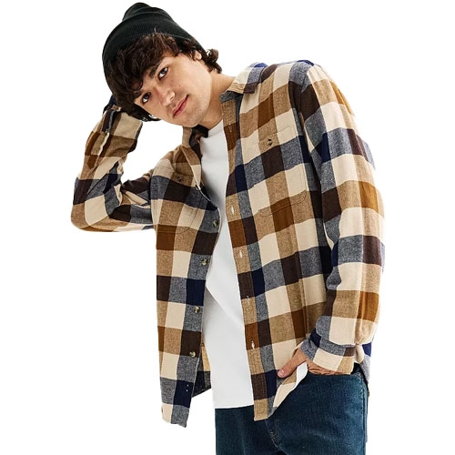 Men's super soft flannel shirt featuring a large checkered pattern in shades of brown, blue, and cream, paired with a white undershirt and dark pants and accessorized with a black beanie.