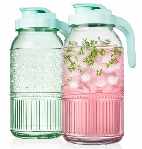 Two glass pitchers with textured designs and mint green lids, one filled with pink liquid, ice, and herbs.