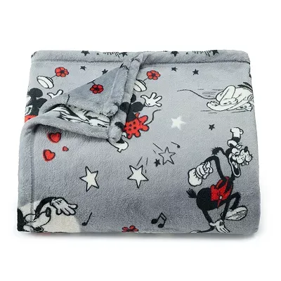 A plush Disney throw featuring classic characters like Mickey Mouse in a playful black, white, and red design against a gray background.