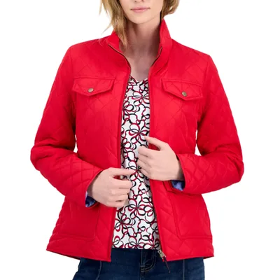 A red quilted jacket with a stand collar, buttoned flap chest pockets, and a front zipper closure, worn over a patterned shirt.