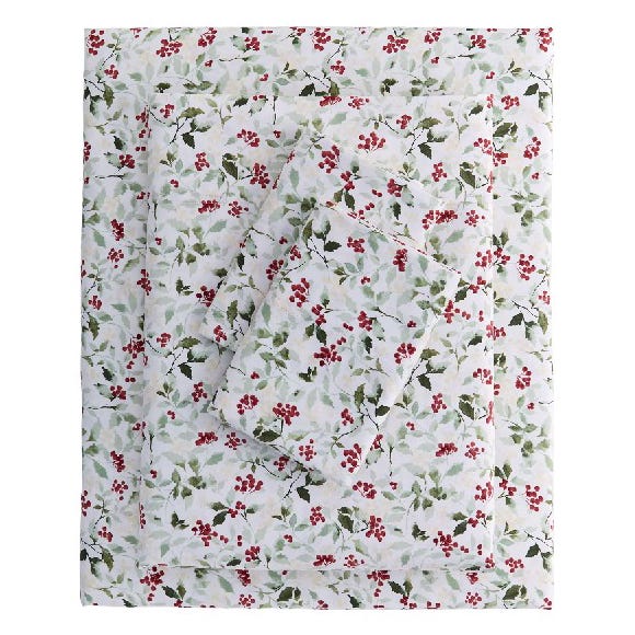 A bedding set featuring a floral pattern with red berries and green leaves on a white background.