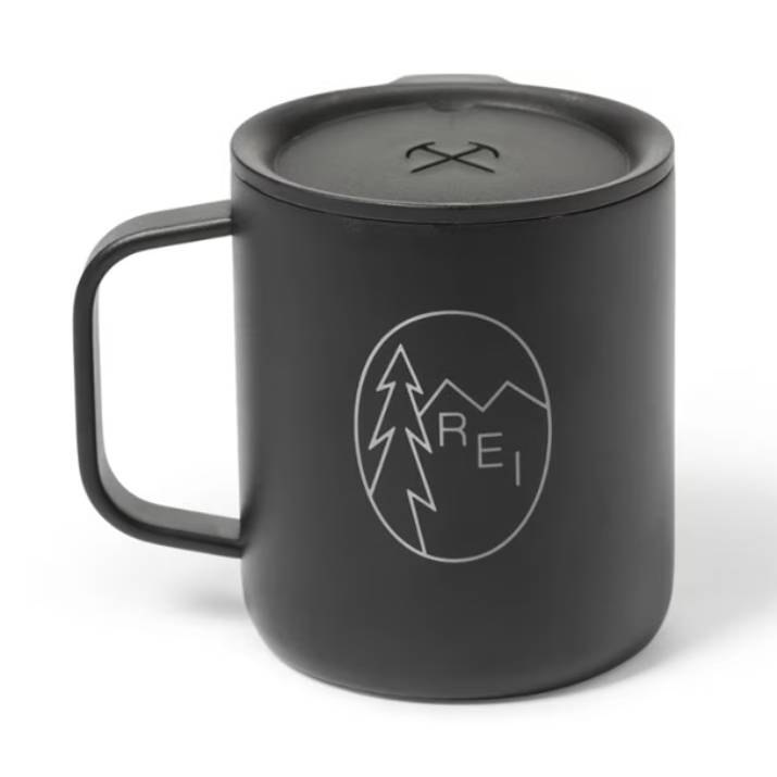 Black camping mug with a lid, featuring a tree and mountain design along with the text \“REI\“.