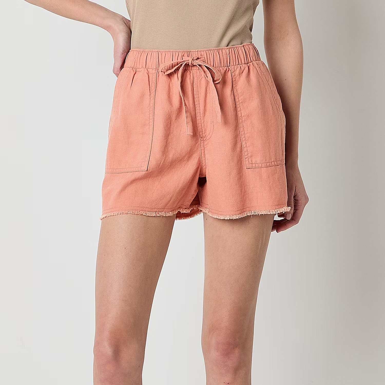 Peach-colored drawstring shorts with frayed hems.