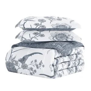 A bedding set with a floral and bird pattern, featuring a comforter and two pillow shams in a monochrome design.
