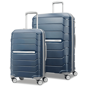 Two blue hard-shell suitcases with horizontal ridges, featuring telescopic handles and four wheels each. The smaller suitcase is placed in front of the larger one.