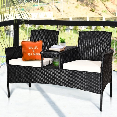 Black outdoor furniture set with two chairs, a loveseat, and a central table, featuring white cushions and an orange decorative pillow.