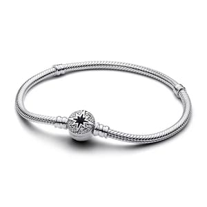A silver bracelet features a snake chain design with a star and crystal-embellished clasp.