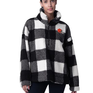A black and white checkered fleece pullover with a Cleveland Browns logo on the chest, featuring a high collar and half-zip design.