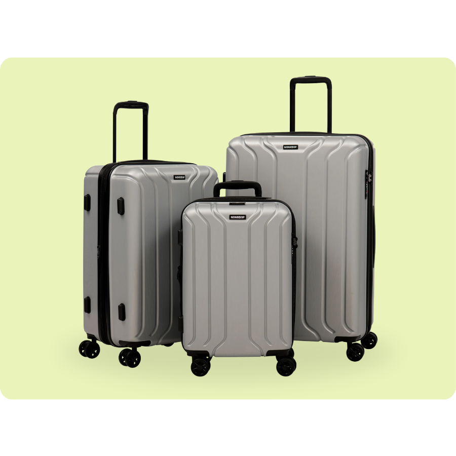 Three silver hard-shell suitcases with four wheels each, varying in size, positioned against a light green background.
