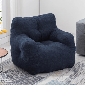 A navy blue armchair with a soft, plush texture and a cozy, tufted design, suitable for living room settings. The chair is placed on a patterned rug next to a wooden side table with lemons.