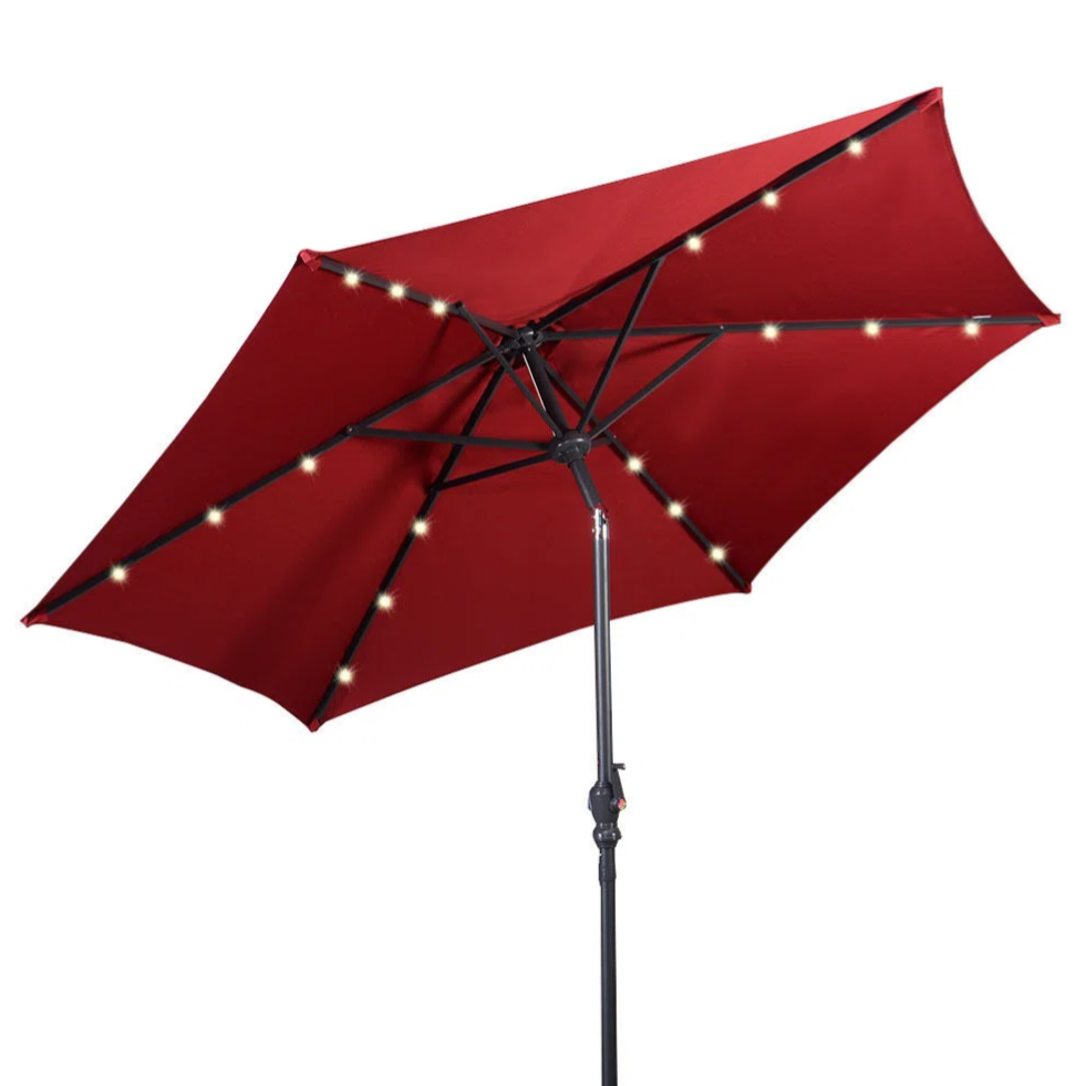 A red patio umbrella with integrated string lights along its ribs, standing on a black metal pole and base.