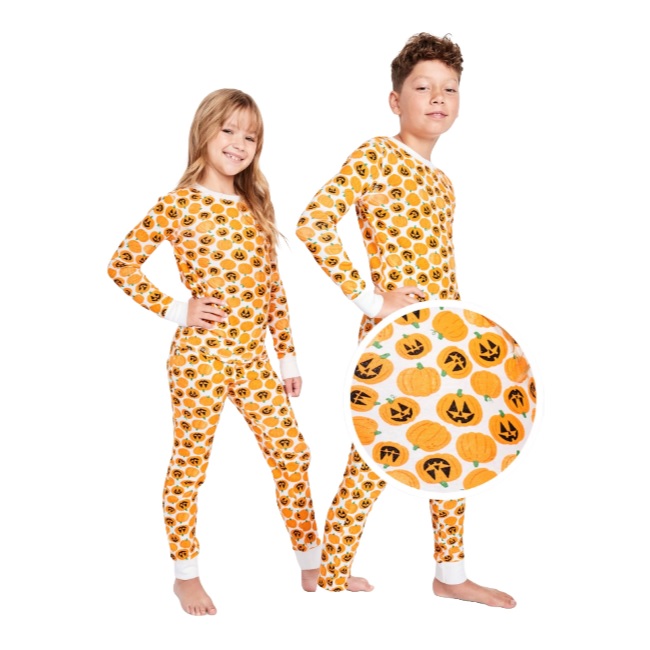 Two children are wearing Halloween-themed pajamas covered in pumpkin and jack-o'-lantern patterns, with white cuffs and collars. A close-up view highlights the orange and black pumpkin designs.