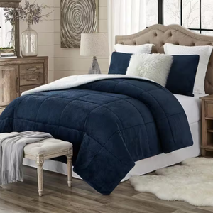 A navy blue, three-piece comforter set with a plush sherpa texture, accompanied by two matching shams, displayed on a bed with neutral-toned decor.