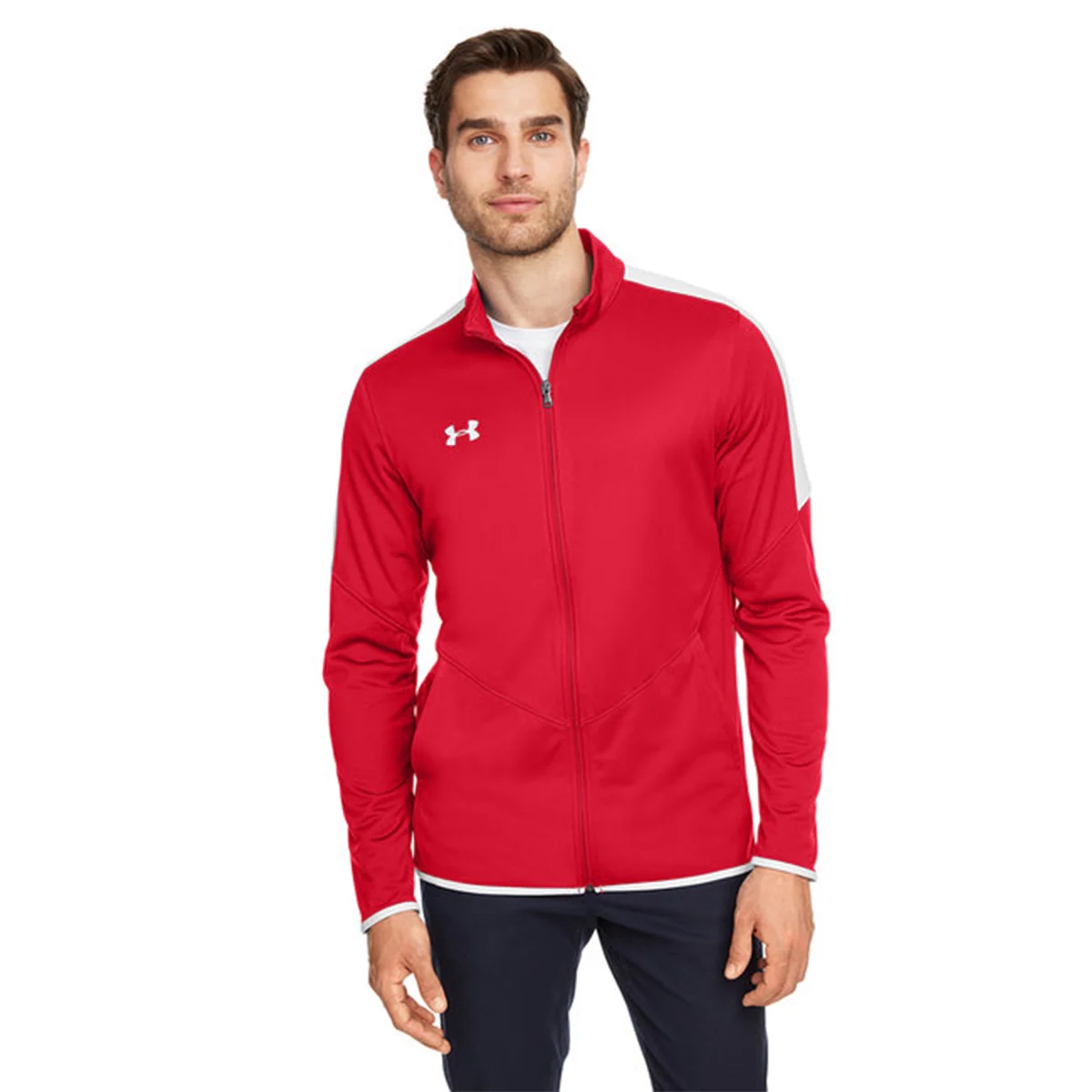 A man is wearing a red Under Armour track jacket with a white logo on the chest, featuring a full zip front and white accents on the cuffs and shoulders.