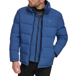 Blue puffer jacket with a zipper closure and CK logo, worn over a black and white striped shirt.