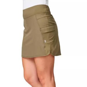 The Free Country Hybrid Skort is a versatile, olive-green skort featuring multiple side pockets and a comfortable, wide waistband, combining the look of a skirt with the practicality of shorts underneath.