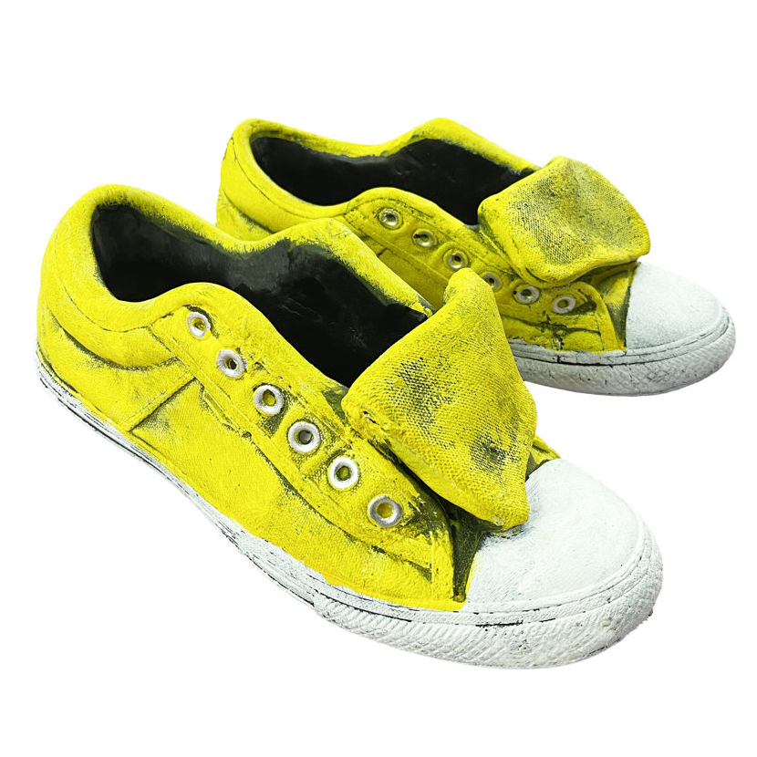 A yellow sneaker planter resembling worn canvas shoes with visible weathering and a white rubber sole, featuring multiple eyelets and an open tongue design.