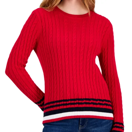 A red cable-knit sweater with navy and white striped trim at the hem and cuffs, paired with blue jeans.