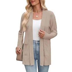 A person wearing a beige cardigan over a white top, paired with light blue jeans. They are accessorized with a necklace, rings, sunglasses, and a shoulder bag.