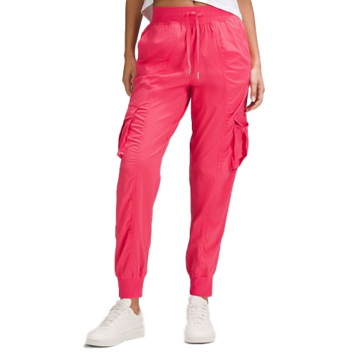 Bright pink joggers made from lightweight material, featuring an elastic waistband with a drawstring, cuffed ankles, and side cargo pockets, paired with white sneakers.