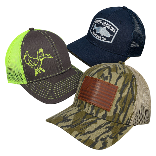 A 3-pack of hats featuring different designs: one with a neon green duck and mesh back, another in navy blue with a \“North Carolina\“ patch, and the third in a camouflage pattern with a leather patch.