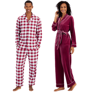 A man in a red and white checked pajama set and a woman in a burgundy velvet pajama set with white trim.