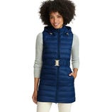 A woman is wearing a blue quilted hooded vest with a gold buckle belt, over a light gray long-sleeve top and white pants.