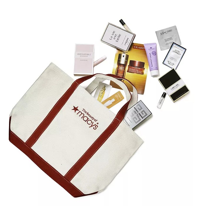 A Macy's tote bag contains an assortment of beauty samples, including fragrances and skincare items from brands like Lancôme, Givenchy, and Clarins.