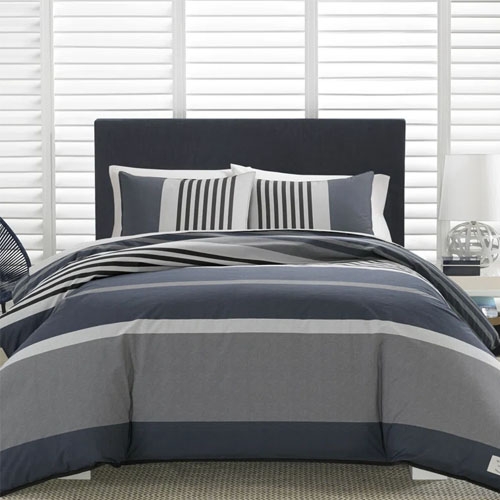 A gray striped bedding set on a bed with a dark headboard, including pillows and a comforter.