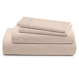 A neatly folded beige bed sheet set includes a fitted sheet, flat sheet, and pillowcases, featuring subtle stitched detailing.