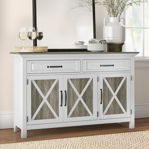 A white 52\“ farmhouse sideboard with two drawers and three cabinet doors featuring an X-pattern design. It has black handles and is topped with glassware and kitchen items, complementing a rustic decor style.