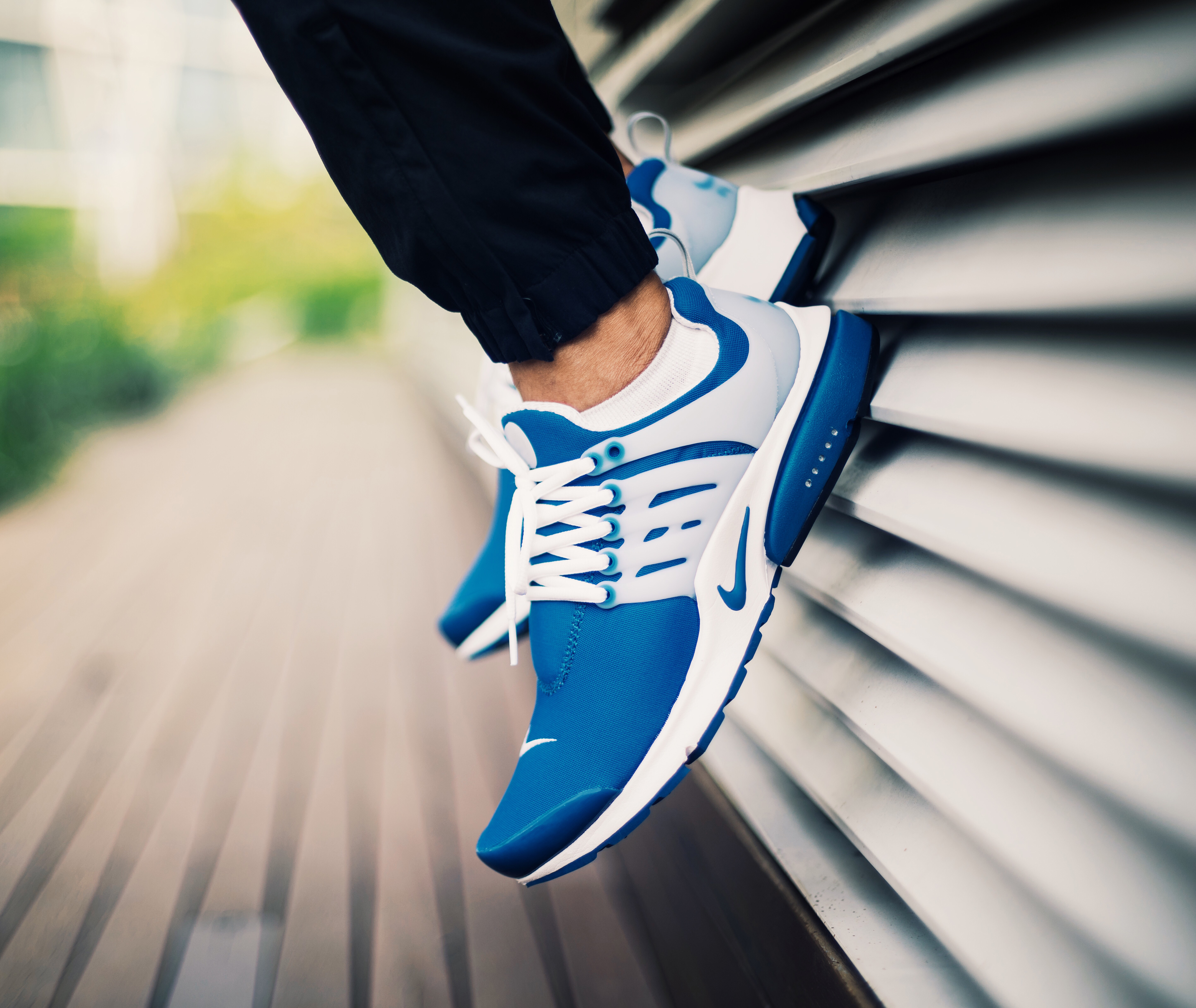 A pair of blue and white sneakers on someone’s feet with white laces.