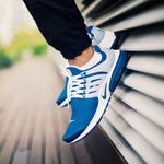 A pair of blue and white sneakers on someone’s feet with white laces.