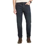 A person wearing dark blue denim jeans paired with brown leather shoes.