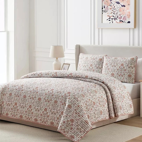 A 3-piece microfiber quilt set includes a quilt with a soft floral damask pattern in muted tones and two matching pillow shams. The set features a light, cozy design suitable for a neutral or pastel-themed bedroom.