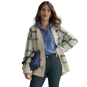 A woman models a beige and green plaid cardigan over a denim shirt, paired with dark green pants, holding a dark blue bag.