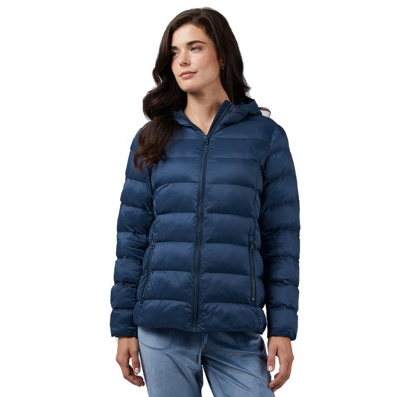 A woman is wearing a navy blue, quilted, packable hooded jacket with a front zipper and side pockets. The jacket has a puffer style for insulation and is designed for casual wear.