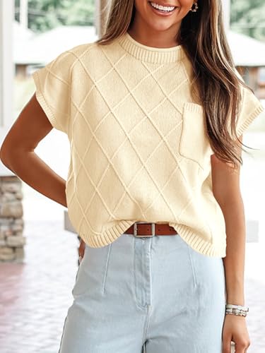 A woman wearing a short-sleeve, light yellow diamond-patterned knit sweater with a small front pocket, paired with light blue high-waisted pants and a brown belt.