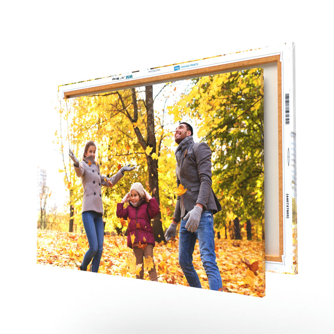 A 24\“ x 36\“ canvas displays a vibrant autumn scene with a family of three enjoying fallen leaves.