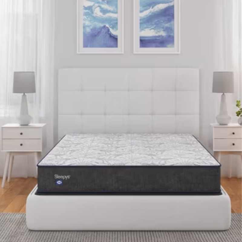 Sleepys mattress on a white upholstered bed frame with a quilted headboard, flanked by two white nightstands with lamps, set against a backdrop of two abstract blue wall art pieces.