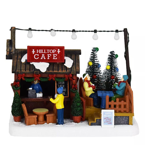 Miniature festive scene of a café surrounded by figures, Christmas trees, and holiday decorations with a \“Hilltop Café\“ sign and lights.
