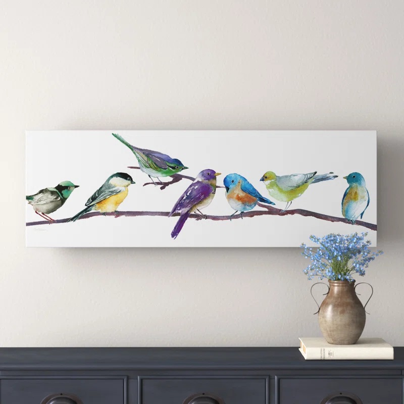Rectangular wall art of colorful birds on a branch, displayed above a console table with a vase and a book.