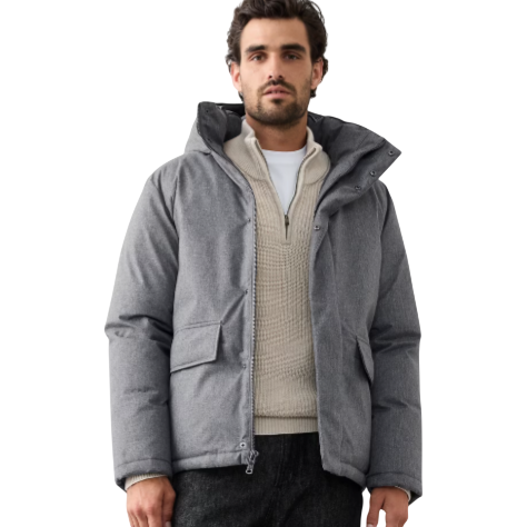 A man wearing a gray puffer jacket, cream textured sweater, black pants, and brown hiking boots.