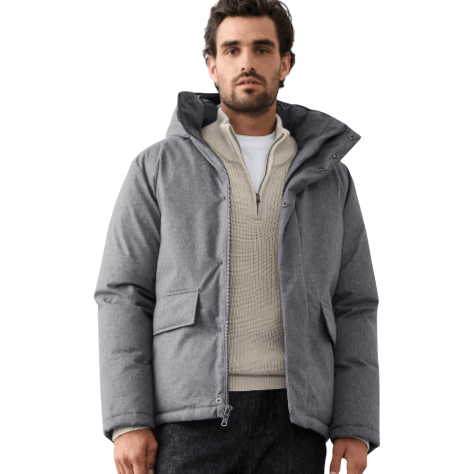 A man wearing a gray puffer jacket, cream textured sweater, black pants, and brown hiking boots.