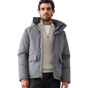 A man wearing a gray puffer jacket, cream textured sweater, black pants, and brown hiking boots.