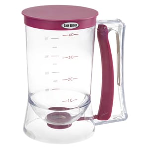 The Chef Buddy Pancake Batter Dispenser is a clear container with measurement markings and a maroon lid, handle, and bottom. It features a trigger handle for easy, precise dispensing of batter.