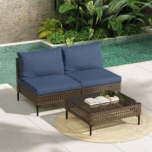 A sectional outdoor sofa with dark blue cushions and a matching wicker coffee table with a glass top, set near a poolside.