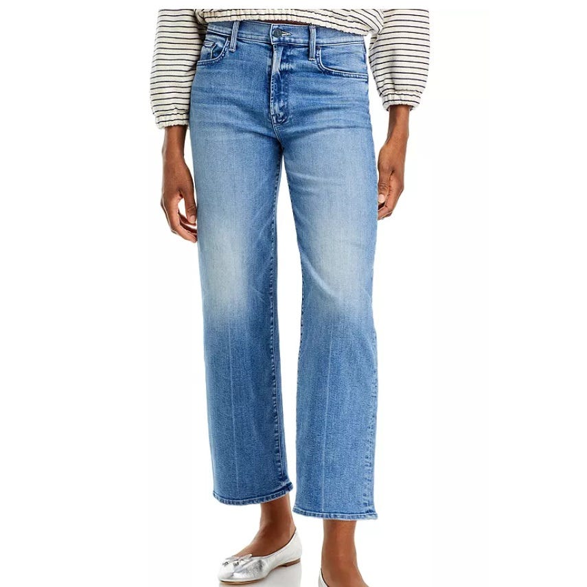 Blue high-waisted, straight-leg jeans with a lightly faded finish, paired with a striped long-sleeve top and silver flats.