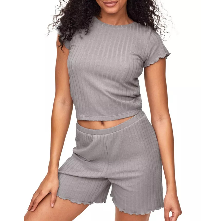 The Adore Me Lilliana set features a gray, ribbed T-shirt with short sleeves and a matching pair of shorts. Both pieces have a comfortable and relaxed fit with subtle ruffled edges for a casual look.