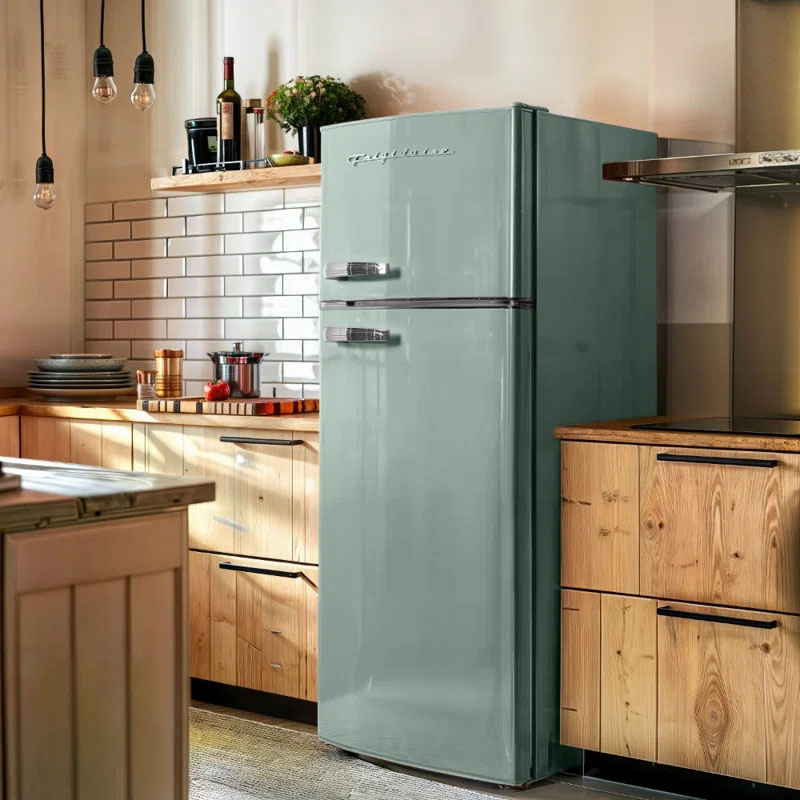 A vintage-style Frigidaire 7.5 cu.ft retro fridge in mint green, featuring classic chrome handles. It complements a warm kitchen setting with wooden cabinets and white subway tile backsplash.
